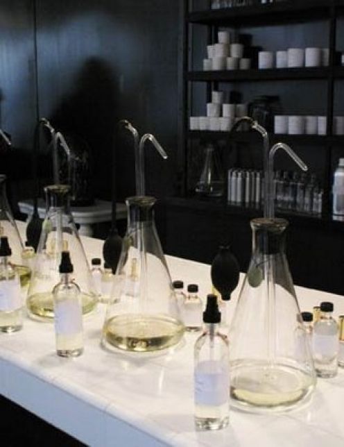 a row of wine glasses sitting on top of a counter next to bottles and beakers