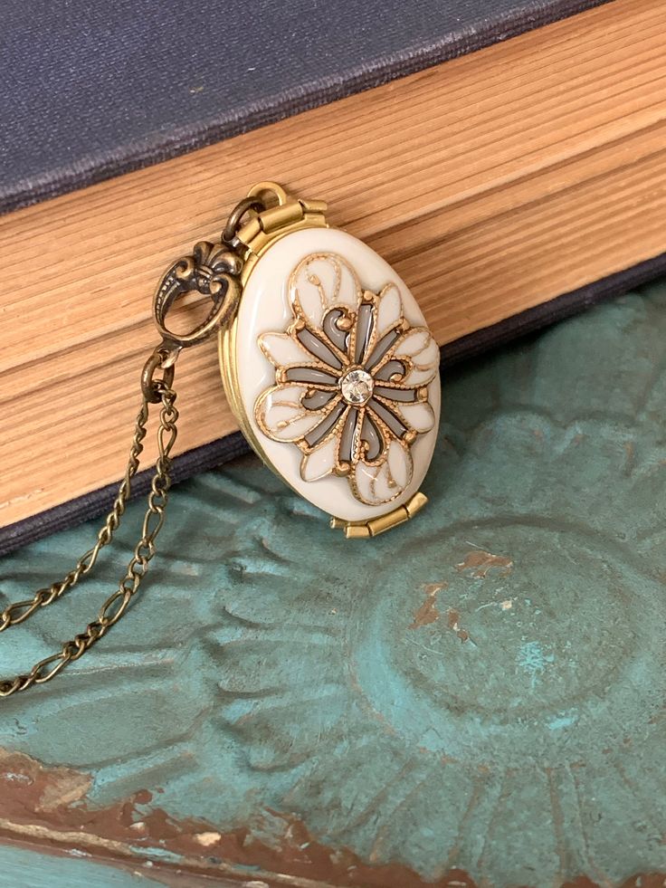 an antique pocket watch sitting on top of a book with chain around it's neck