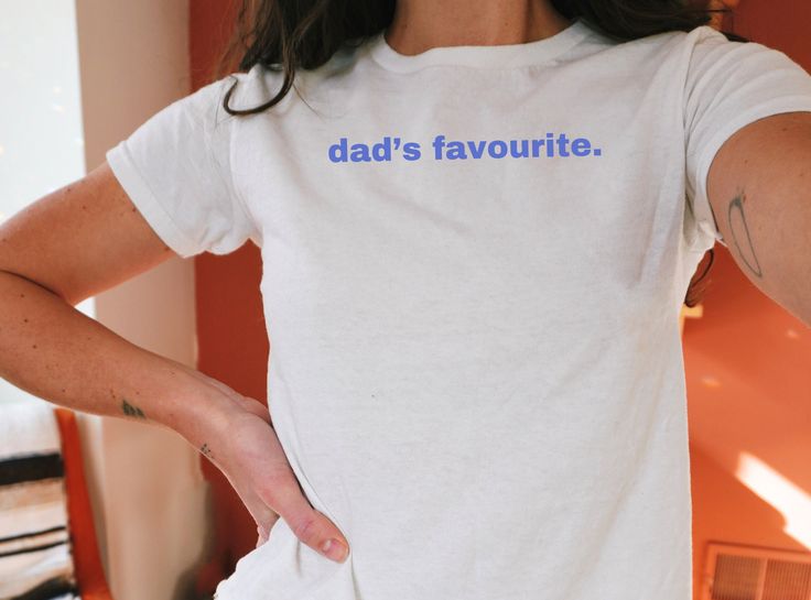 Dad's Favorite - funny trending shirt graphics printed in light blue on a lightweight cotton 90s-style baby tee. Please see the full product description below before making your order! ♥PRODUCTION TIME: 1-5 days (usually 2-3 days) ♥SHIPPING TIME: 3-5 days ♥PRODUCT DESCRIPTION: TRANSPARENCY DISCLAIMER / DISCLOSURE: these are "YOUTH" tees that fit the look of a baby tee that we all know & love! Super soft cotton and lightweight quality. 100% Soft cotton for the solid colors (fibre content may vary Graphic Print Streetwear Tops, Retro Cotton T-shirt For Father's Day, White Pop Culture Tops With Slogan, White Pop Culture Slogan Tops, White Pop Culture Slogan Top, Cotton Tops With Funny Texts In Pop Culture Style, Cotton Tops With Funny Text In Pop Culture Style, Blue Tops With Screen Print For Father's Day, Blue Screen Print Tops For Father's Day