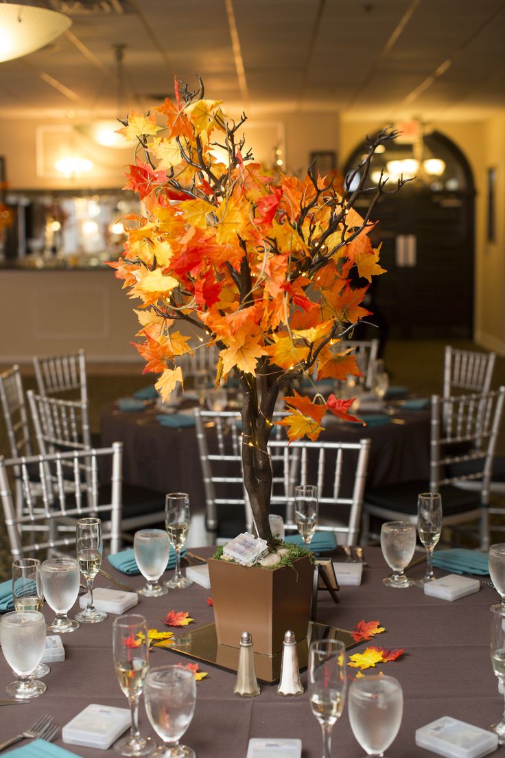 the table is set with glasses, plates and vases for an autumn themed centerpiece