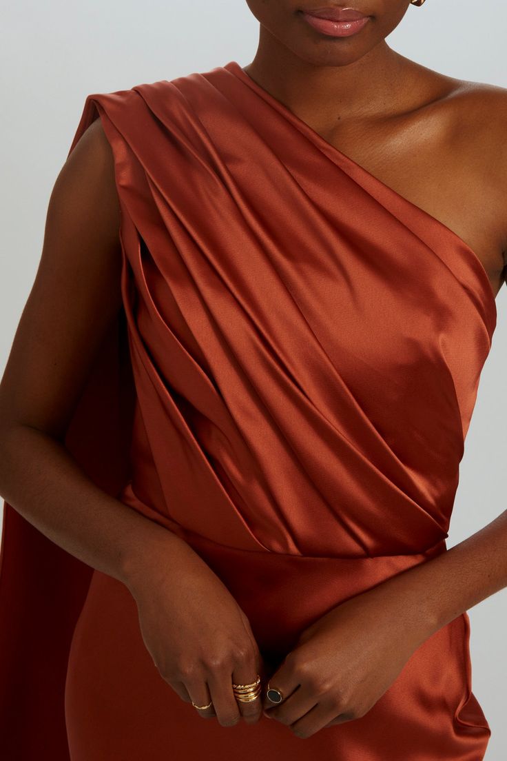 Fluid satin fit-to-flare gown bias draped one-shoulder dress. Shown in Copper.