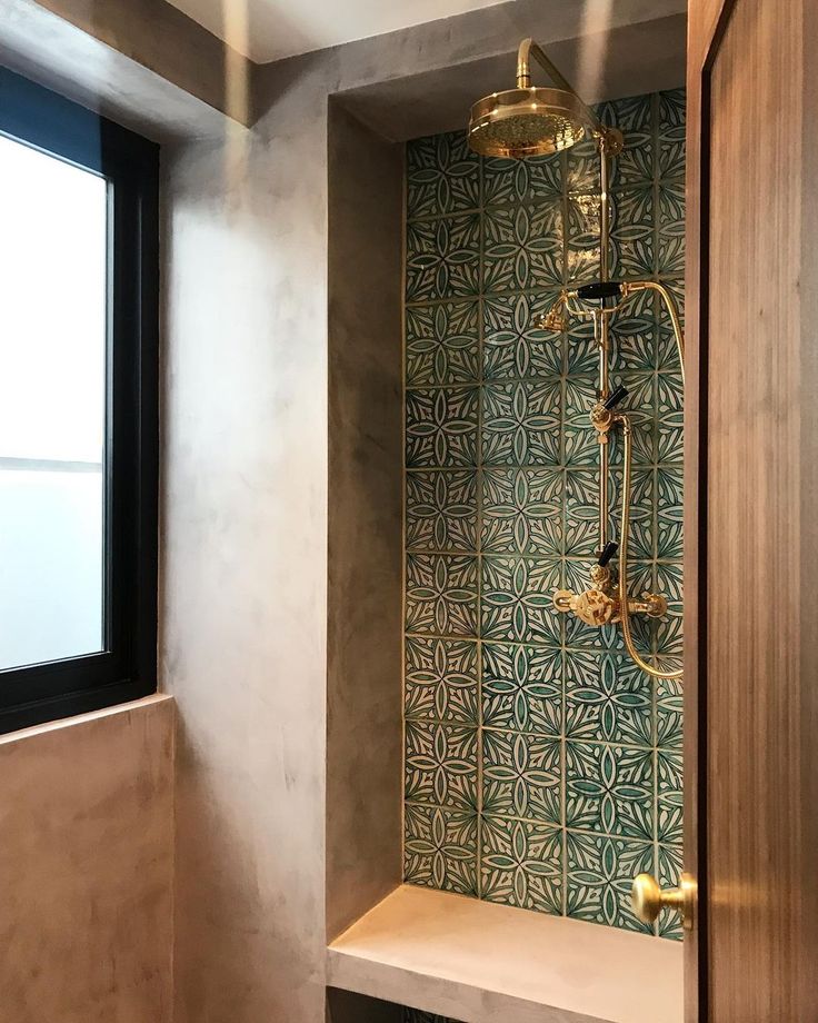 a bathroom with a shower head, window and tiled wall in the corner next to it