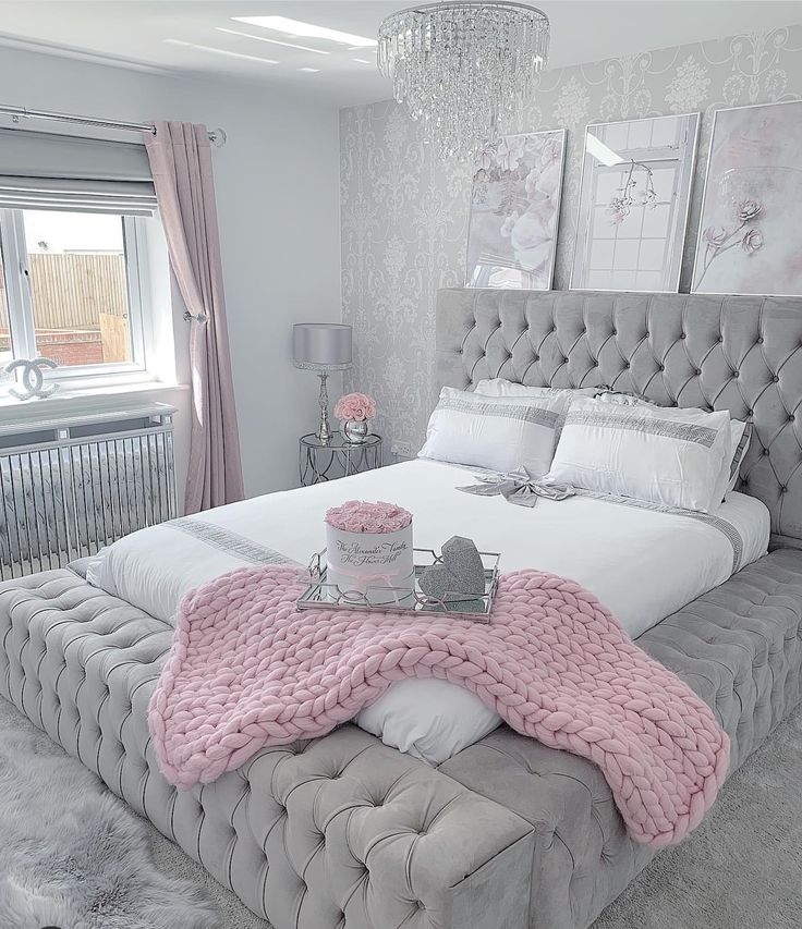 a bed with a pink blanket on top of it next to a chandelier