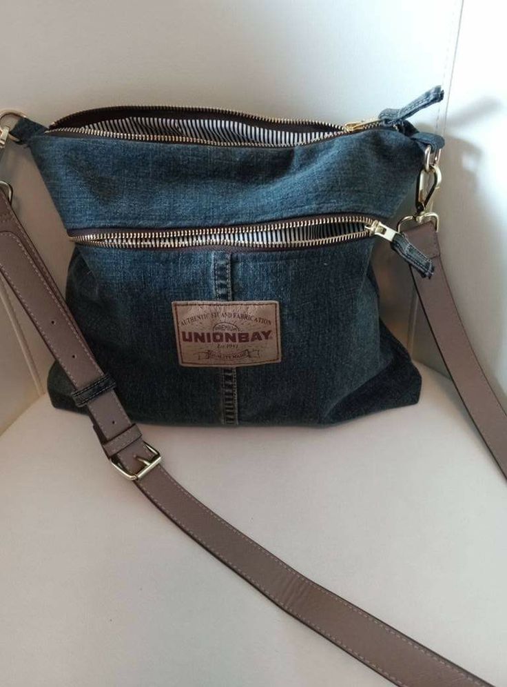 a denim purse with zippers on the front and side, sitting on a white surface