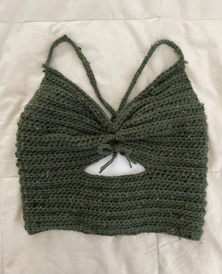 a crocheted crop top with a knot at the front and back, on a white sheet