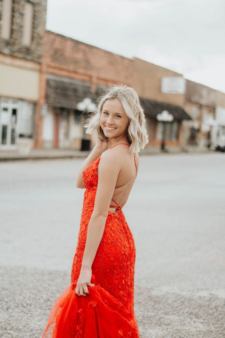 a woman in an orange dress standing on the street