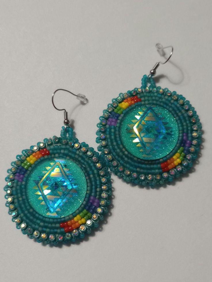 a pair of earrings with beaded designs on them