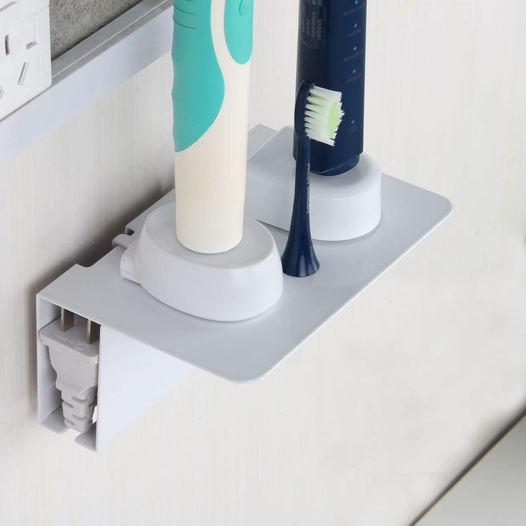 two toothbrushes sitting on the edge of a bathroom shelf next to each other