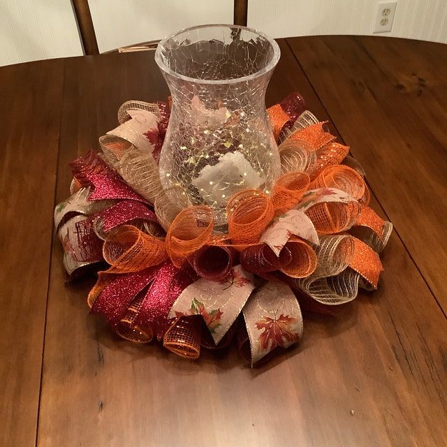 a glass vase sitting on top of a wooden table next to a pile of ribbons