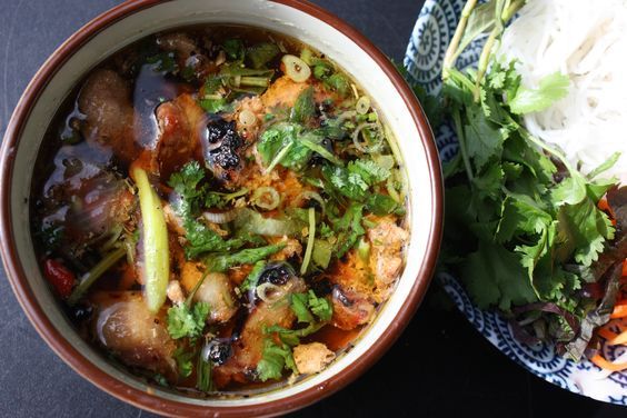 a bowl of food next to a plate of rice and salad on a black table