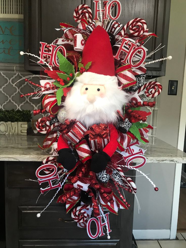 a christmas wreath with a santa clause on it and candy canes hanging from the front door