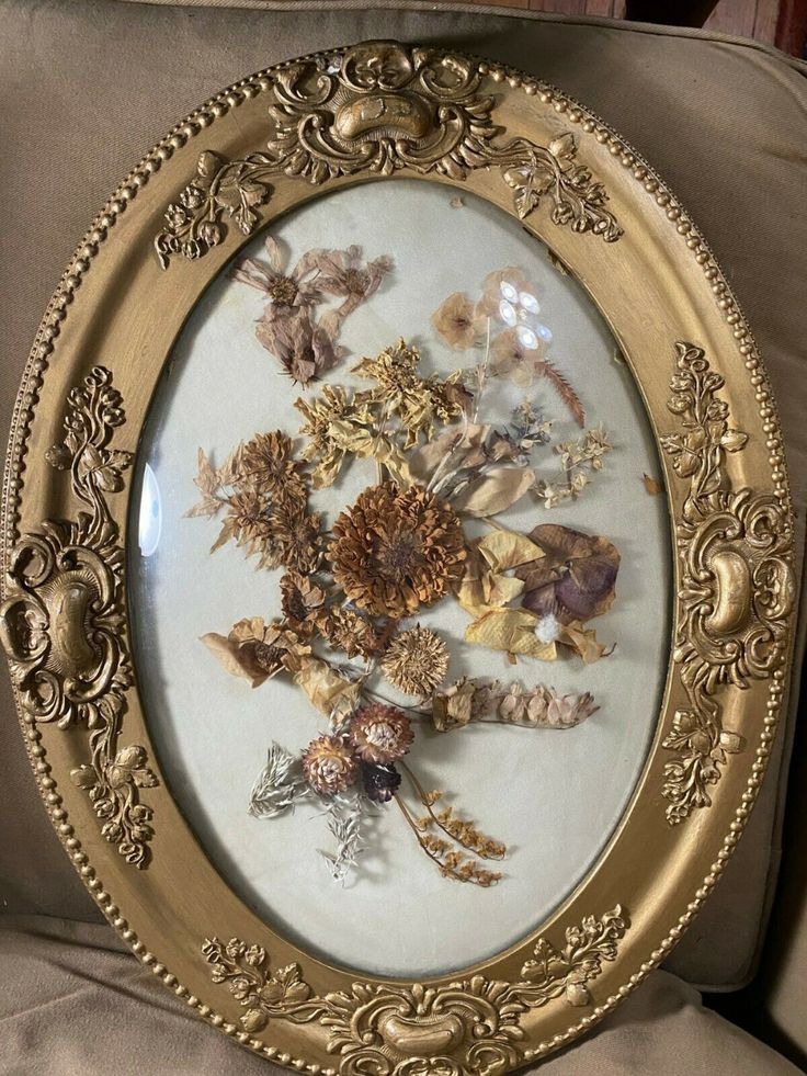 an ornate gold frame with dried flowers in it on a chair cushion, close up