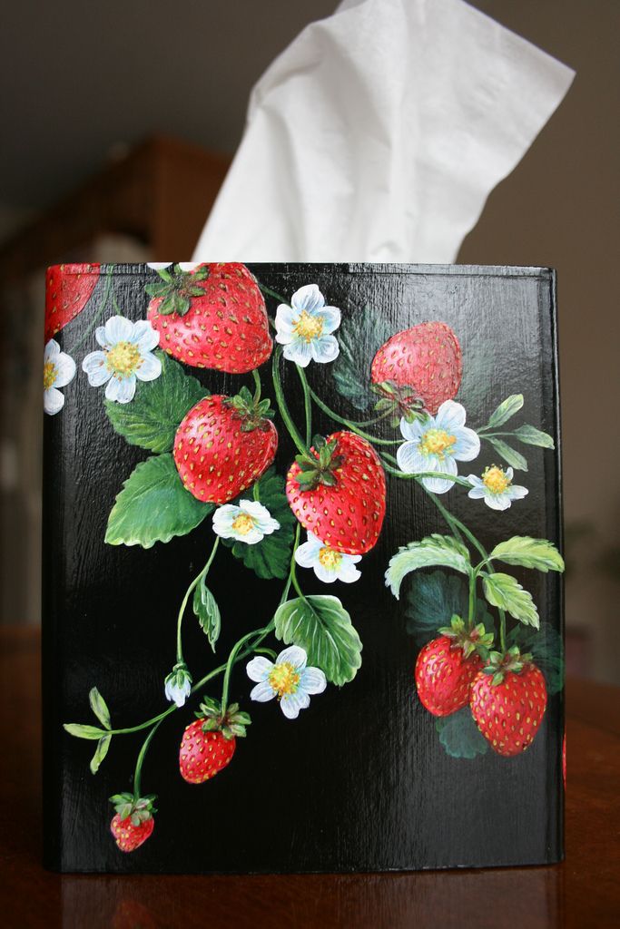 a tissue dispenser sitting on top of a wooden table with strawberries and flowers painted on it