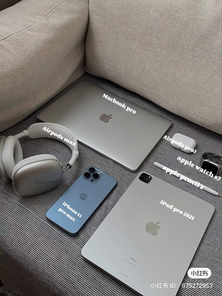 an apple laptop, headphones, and other electronics are on the couch next to each other