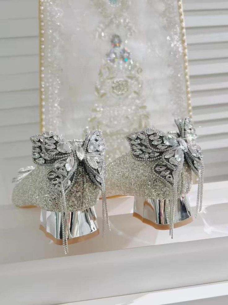 two silver bells with bows on them sitting next to a window sill in front of a white wall