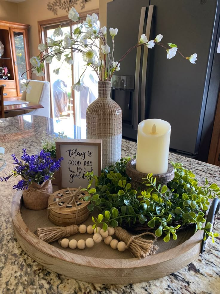 a tray with flowers and candles on top of a kitchen counter