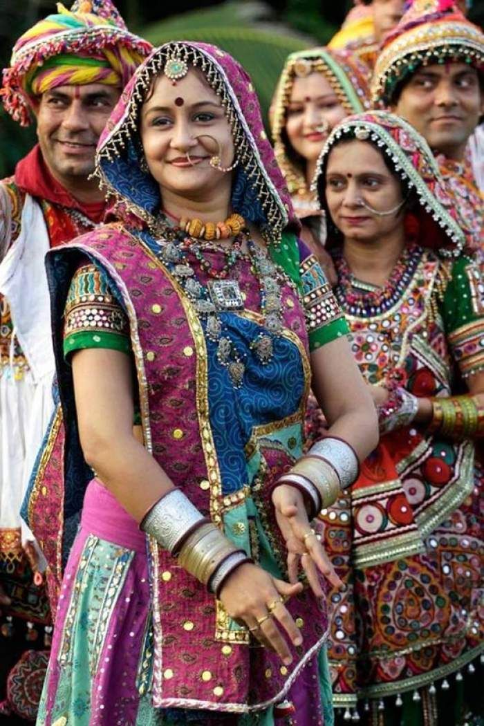 a group of women dressed in colorful clothing and headgear standing next to each other