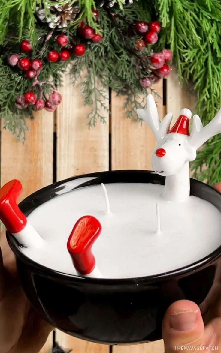 someone is holding a bowl with candles in it that look like reindeers and snowmen