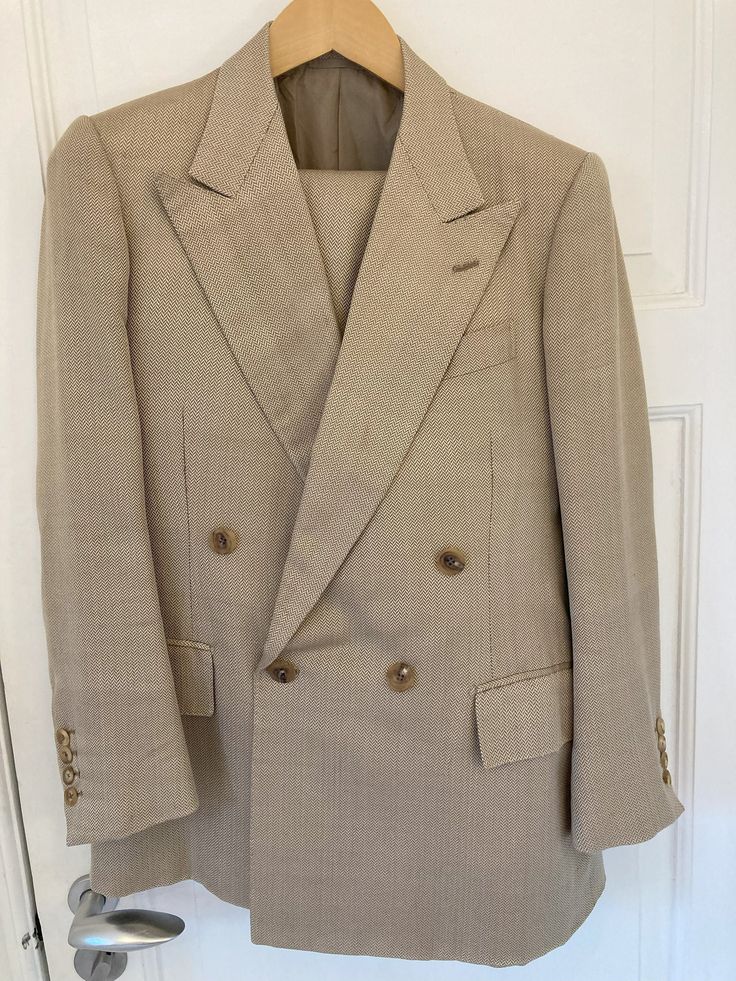 A classic, double-breasted tan suit by the late Edward Sexton of Savile Row 35, made of wool and silk with a stunning herringbone pattern. The iconic, large lapels and roped shoulders alongside details such as hand-sewn buttonholes. The trousers feature two side adjusters and have no pleats. The condition is excellent. Truly a unique and one-of-a-kind suit. An Edward Sexton suit begins at about 5000 euros.  Shoulders: 41cm - 16 inches Sleeve length: 61cm (with 3cm of fabric to let out) - 24 inch Timeless Beige Wool Suits, Elegant Brown Double Breasted Suit With Suit Collar, Elegant Brown Wool Double Breasted Suit, Elegant Brown Double Breasted Suit, Elegant Brown Double-breasted Suit, Tailored Beige Wool Suit, Beige Wool Suits For Professional Tailoring, Beige Wool Suits For Tailoring, Beige Wool Suit For Semi-formal Occasions