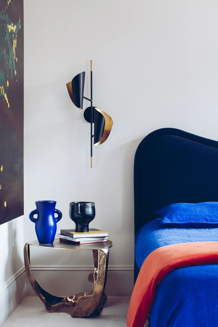 a bedroom with a blue bed and two vases on the table next to it