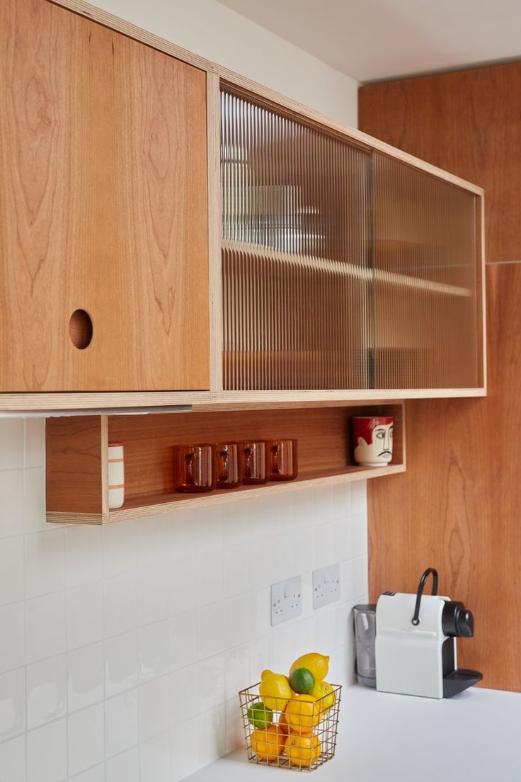 a kitchen with wooden cabinets and white counter tops, along with a basket of fruit on the counter