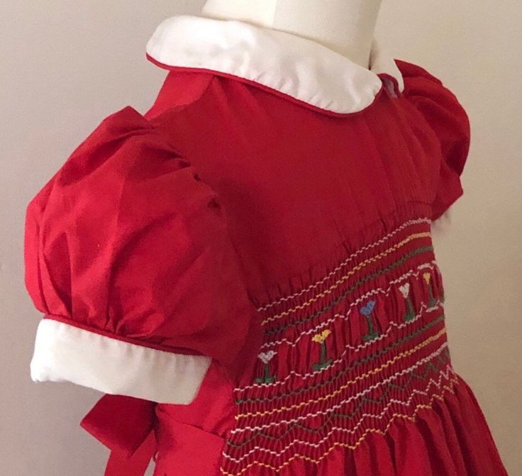 "Beautiful cherry red floral embroidered smocked dress. White Peter Pan collar and puff sleeve cuffs trimmed with red piping.Full skirt & pull back bow sashes,4 top back buttons.No fabric table/made in Hong Kong /feels washes an iron's like cotton or cotton blend/pit to pit 10 1/2\"/waist -About the same but can be pulled back with tie sash/length (shoulder to bottom hem) 24\" w/a 2 3/4\" hem available/smoke free home(135)" Fitted Red Smock Dress, Cute Red Puff Sleeve Dresses, Cute Long Sleeve Fitted Smocked Dress, Cute Red Smock Dress, Red Smocked Dress With Ruffles And Short Sleeves, Red Smocked Bodice Dress For Holiday, Red Fitted Cotton Smocked Dress, Fitted Red Cotton Smocked Dress, Red Holiday Dress With Smocked Bodice