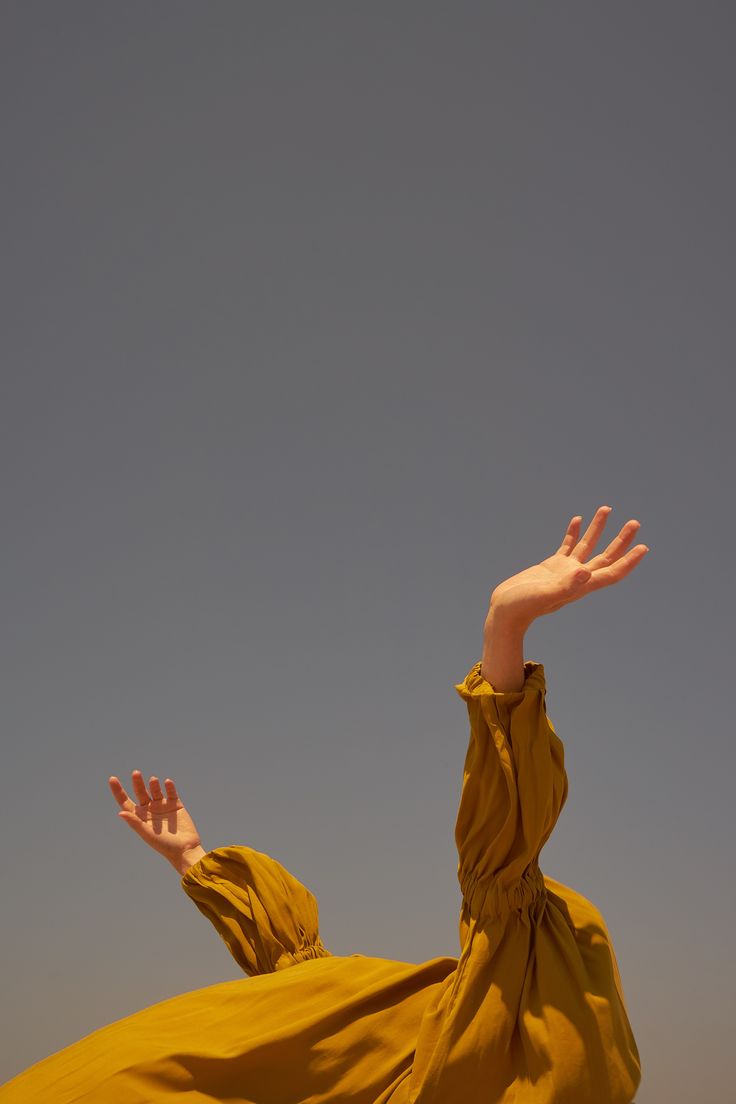 a woman in a yellow dress is flying through the air with her hands out to catch a frisbee