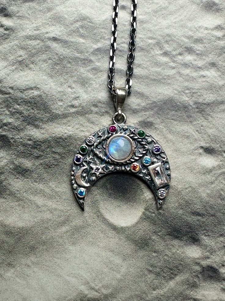 MOONSTONE CRESCENT MOON Third Eye Celestial Sterling Silver Necklace 🌙 Unveil the mystical charm with our Crescent Moon Necklace, beautifully crafted in sterling silver. At the heart of the crescent, a captivating evil eye design is meticulously embedded with a moonstone, surrounded by an array of multicolored gemstones that add a vibrant, eye-catching touch. This piece combines symbolic meanings and aesthetic elegance. The crescent moon, often associated with renewal and cycles of change, perfectly complements the evil eye, which is celebrated as a symbol of protection and mystical watchfulness. Embellished with an assortment of gemstones, this necklace not only wards off negativity but also promotes emotional balance and strength. It's perfect for those who embrace both the evil eye's p Spiritual Crescent Sterling Silver Jewelry, Sterling Silver Crescent Spiritual Jewelry, Spiritual Sterling Silver Crescent Jewelry, Silver Necklace With Moon Charm, Unique Silver Necklace With Moon Charm, Mystical Moon Charm Sterling Silver Necklace, Mystical Sterling Silver Necklace With Moon Charm, Unique Moon-shaped Moonstone Necklace, Silver Crescent Bohemian Jewelry