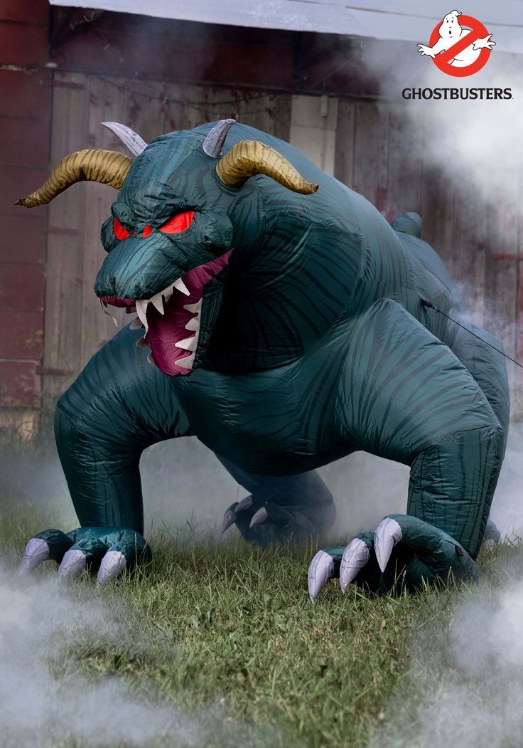 an inflatable dragon with red eyes and large horns on its head is standing in the grass