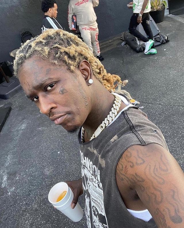 a man with dreadlocks holding a coffee cup