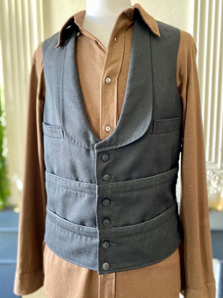 Authentic black French waiter's vest, multi-pocket, in thick cotton on the front and fine satin synthetic on the back. 8 pockets in bands around the waist, 2 chest pockets, 1 inside pocket, black glass buttons (probably not original but old nonetheless, maybe even older than the piece itself), rounded tuxedo collar at the bottom, adjustable tab with a metal buckle at the back. It is vintage without a doubt but for many classic pieces like certain work uniforms, it is difficult to date it precise Cotton Workwear Vest With Multiple Pockets, Cotton Work Vest With Multiple Pockets, Classic Black Cotton Sweater Vest, Retro Cotton Vest With Buttons, Classic Cotton Denim Vest With Pockets, Vintage Denim Vest For Work With Pockets, Vintage Fitted Denim Vest With Buttons, Fitted Cotton Denim Vest With Pockets, Black Cotton Vest With Buttons