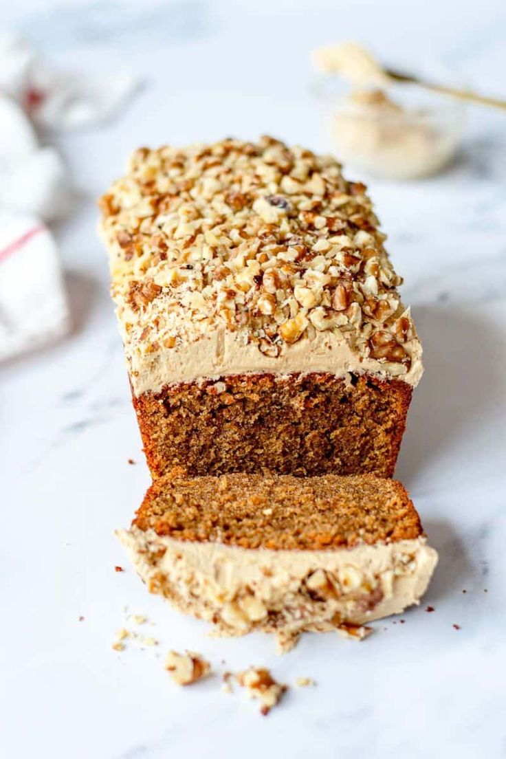 a loaf of carrot bread with nuts on top and one slice cut off from it