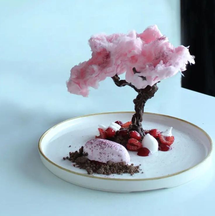 a white plate topped with a small pink tree and ice cream on top of it