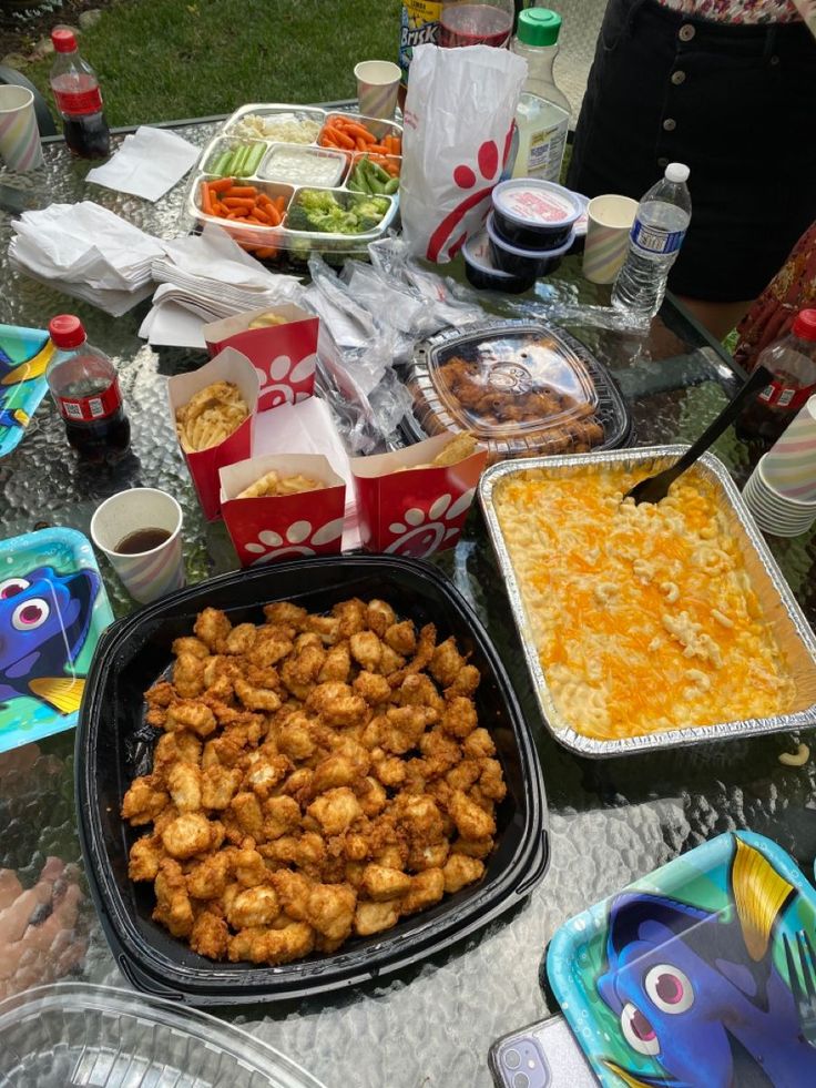 a table full of food including chicken and other foods, drinks and condiments