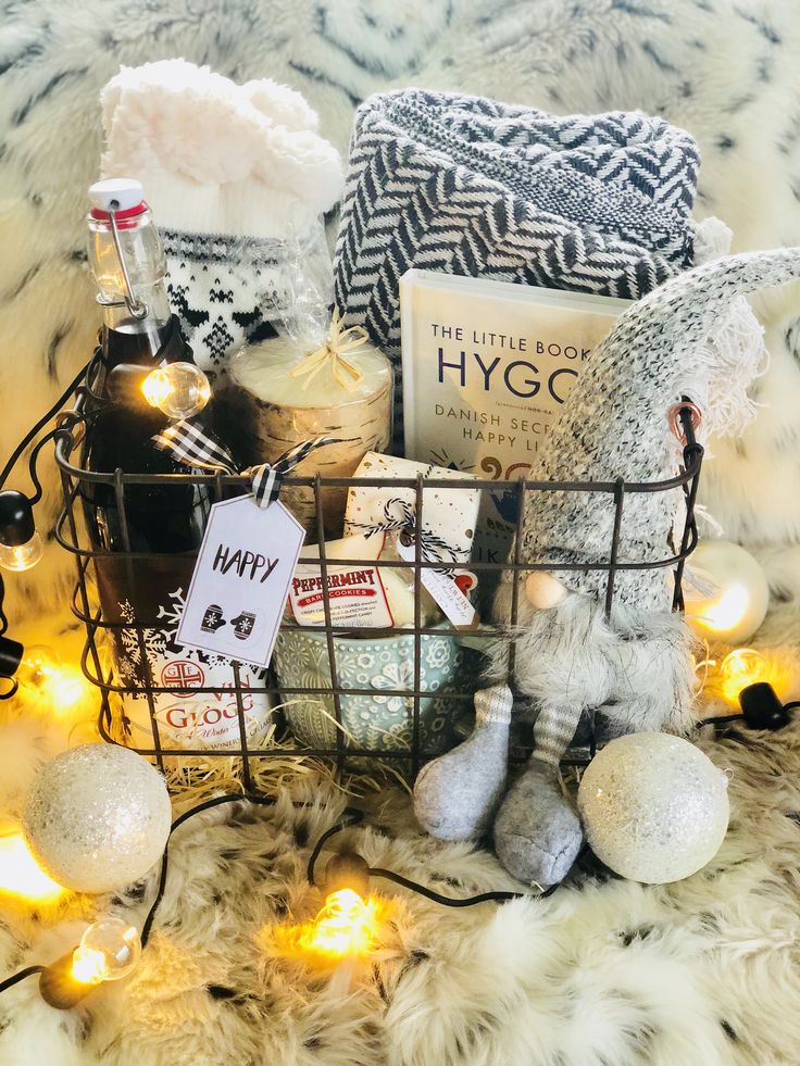 a basket filled with books and gifts on top of a fur covered floor next to christmas lights