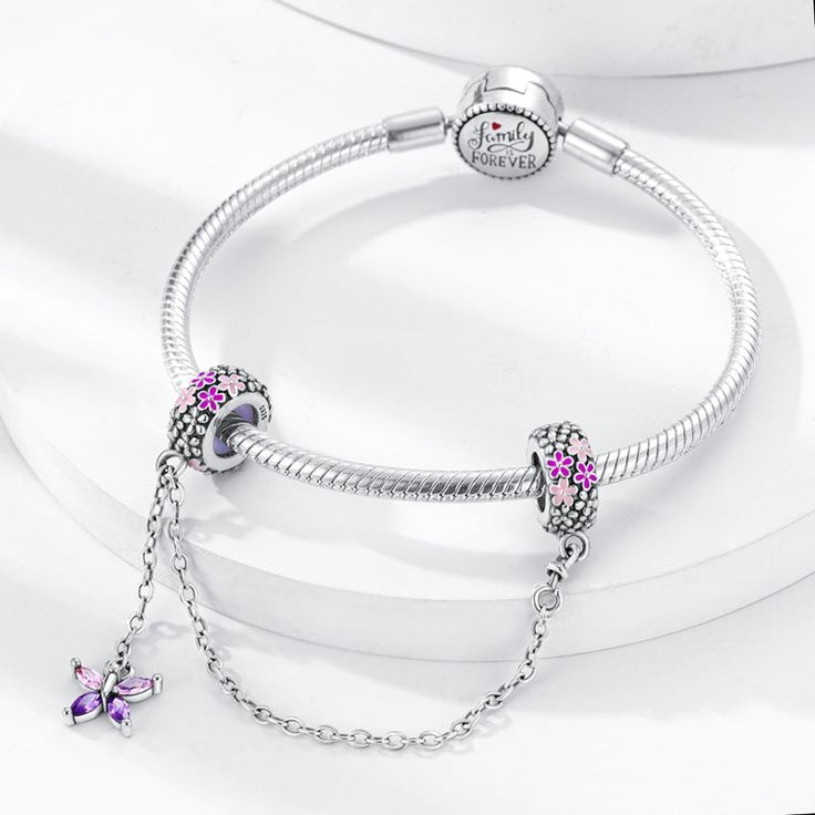 925 Sterling Silver safety chain charm with silicone stoppers, featuring a dangling purple butterfly and flowers on the charm’s rings. Designed with sparkling purple zircon gemstones and smooth pink and purple enamel. Tell your story with each charm and create a bracelet that reflects who you are and what's important to you. Your style. Your bracelet. Your story. Features: Material: 925 Sterling Silver, Zircon, Enamel, SiliconeDesign: Purple ButterflyLength: 5.8 cm / 2.3”Fits 0.3 cm / 0.1" BraceletsCollection: Safety Chains Shipping Info: United States / Canada / Australia: 10 - 15 daysEurope: 10 - 15 daysUAE: 17 daysOther Countries: 20 - 40 days Hassle Free Returns: If you are not completely satisfied with your purchase, you can send it back to us for a refund. Bee Dog, Butterfly And Flowers, Purple Bracelet, Charm Beads, Dog Flower, Safety Chain, Charm Pendant Necklace, Purple Butterfly, Diy Pendant