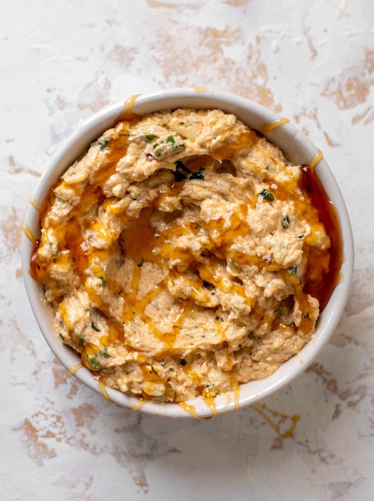 a white bowl filled with hummus and sauce