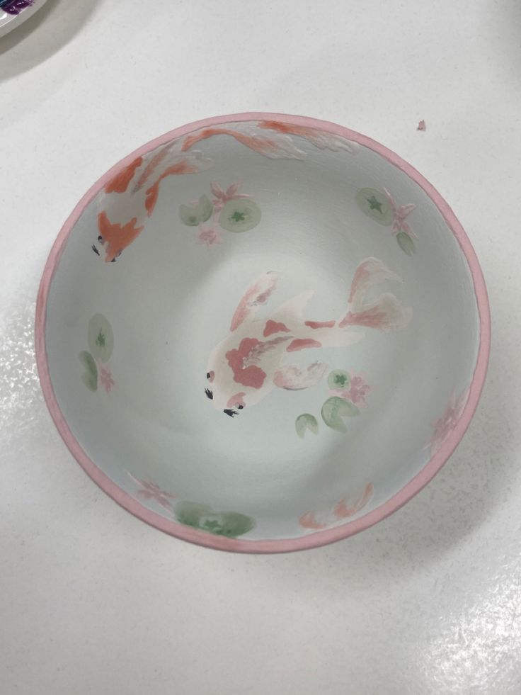 a white bowl with pink and green designs on it