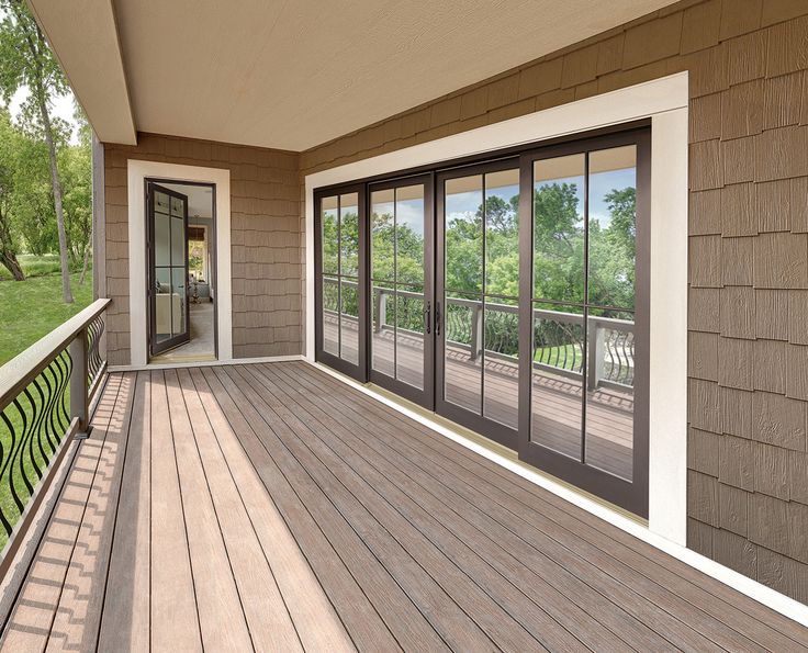 an empty porch with sliding glass doors on the side and grass in the back ground