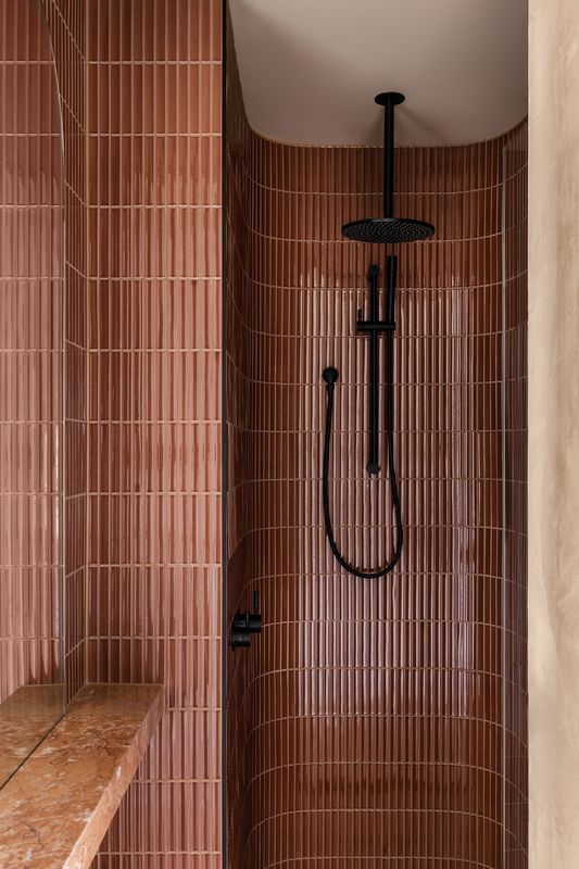 a bathroom with brown tiles and a black shower head