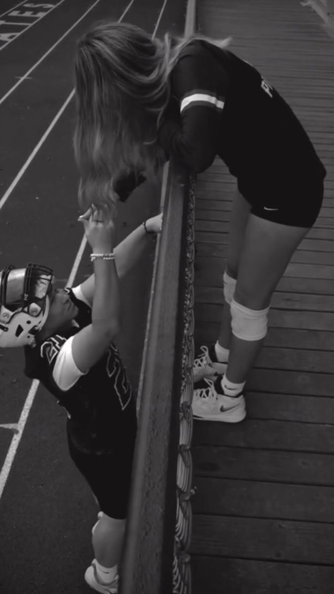 a little boy leaning against a fence on top of a tennis court while holding a glove