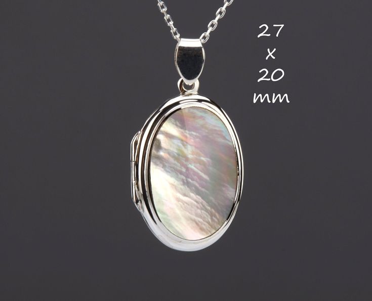 An unique photo locket necklace with an oval mother of pearl set on the front of the locket:  1.  a large solid oval sterling silver locket - 27 x 20 x 7.6 mm (measured without the bale) and weighs 6.5 grams      Its front has a piece of mother of pearl (23 x 16 mm) set in a raised bezel.      Its back is plain and can be engraved with initials or a few words. 2. It has two photo slots insides. Photo insertion service available (selected through the pulldown menu). If you choose this service, pl White Round Locket Necklace For Keepsake, White Round Locket Necklace, White Oval Sterling Silver Locket Necklace, White Oval Locket Necklace In Sterling Silver, Elegant White Locket Necklace For Keepsake, White Oval Pendant Locket Necklace As Gift, White Oval Pendant Locket Necklace, Elegant White Oval Pendant Locket Necklace, White Oval Keepsake Necklace