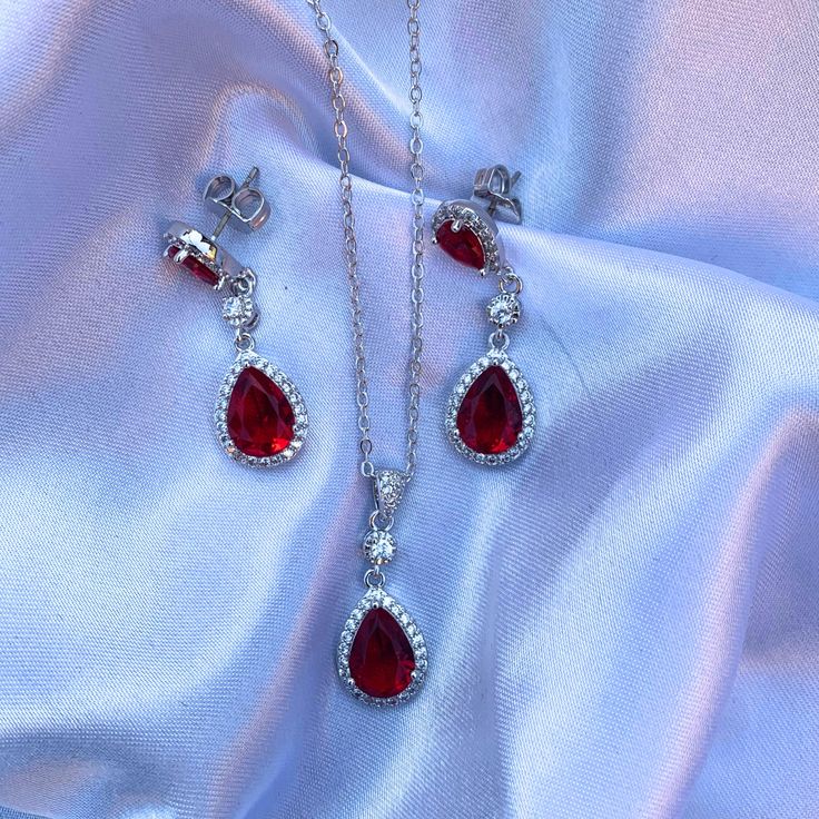 Introducing our exquisite Red Ruby 925 Sterling Silver Women's Infinity Teardrop Pendant Necklace & Dangle Earrings Bridal Set. This elegant set is designed to add a touch of sophistication and charm to any bridal ensemble. Crafted with high-quality 925 sterling silver, each piece features a stunning infinity design adorned with radiant red ruby gemstones, symbolizing eternal love and passion. The teardrop pendant gracefully hangs from a delicate chain, perfectly complemented by the matching dan Red Drop Jewelry With Matching Earrings, Formal Ruby Teardrop Pendant Jewelry, Sterling Silver Jewelry Sets For Wedding On Valentine's Day, Elegant Jewelry Sets With Matching Earrings For Valentine's Day, Elegant Teardrop Pendant Jewelry For Valentine's Day, Elegant Pear-shaped Jewelry For Valentine's Day, Formal Red Dangle Jewelry Sets, Elegant Valentine's Day Jewelry Sets With Matching Earrings, Elegant Valentine's Day Teardrop Pendant Jewelry