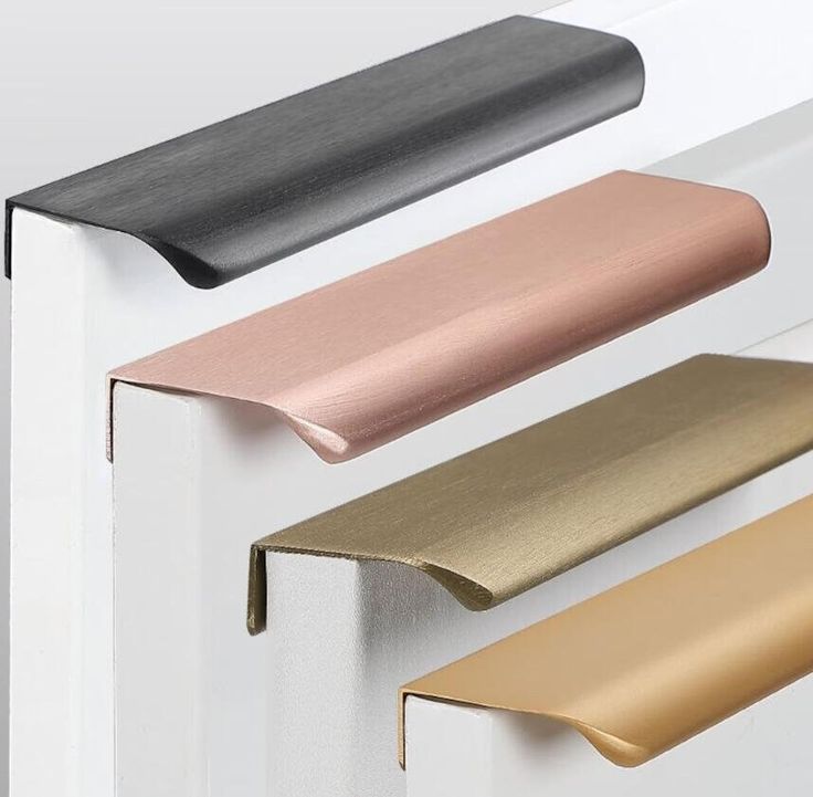 three different colors of door handles on a white cabinet with gold, black, and silver