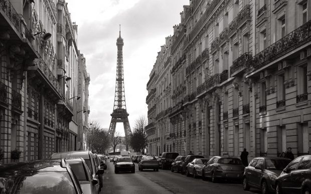 the eiffel tower is in the distance from cars parked on the side of the street