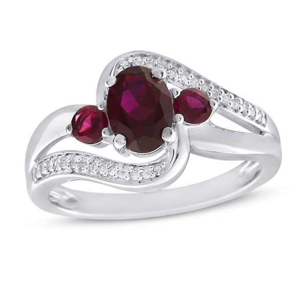 This beautiful ring springs to life with rich colorful hues. An opulent oval-cut lab-created ruby is framed with a pair of round-cut lab-created rubies creating a vibrant focal point. Graceful sweeping bands traced with bright round-cut white lab-created sapphires add extra shimmer and shine. The ring is fashioned in stylish sterling silver. Oval Ring With Lab-created Ruby And Accent Stones, Silver Ruby Ring With Three Stones In Oval Shape, Three Stone Oval Ruby Ring, Oval Lab-created Ruby Jewelry With Accent Stones, Oval Lab-created Ruby Diamond Ring With Accent Stones, Oval Ruby Birthstone Ring With Diamond Accents, Oval Birthstone Ring For Valentine's Day, Oval Ruby Ring With Diamond Accents For Promise, Red Oval Jewelry With Gemstone Accents