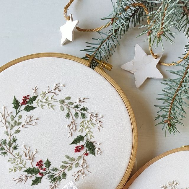 two cross stitch christmas wreaths are on the table