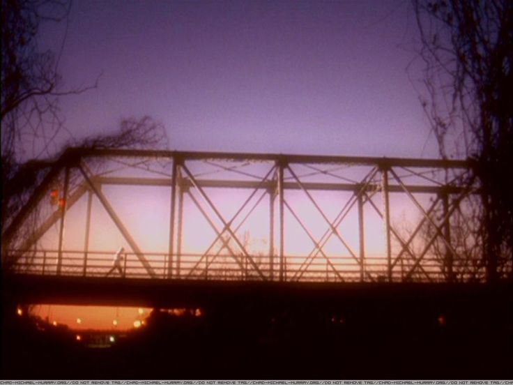 the sun is setting over an old bridge