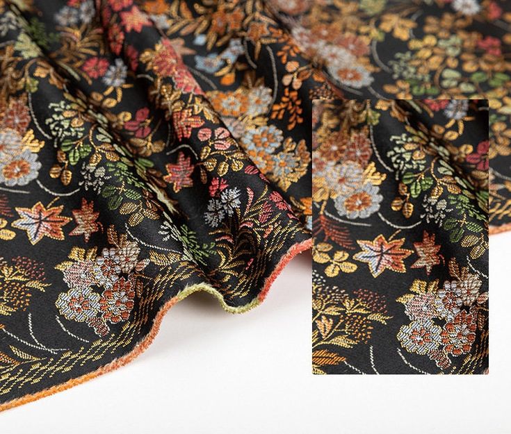 the fabric is black with colorful flowers and leaves on it's side, as well as an orange border