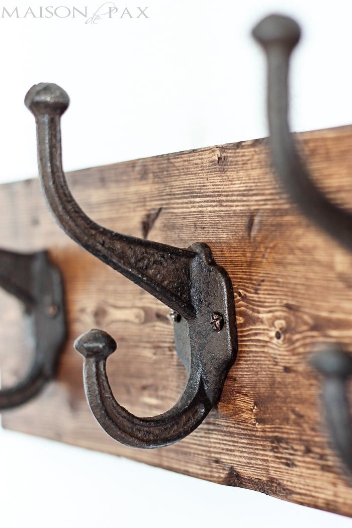 an iron hook is attached to a wooden board with two hooks on it that are hanging from the wall